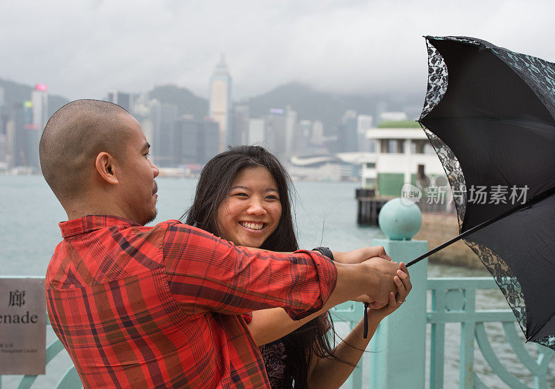 一对夫妇在恶劣天气/下雨中奋力撑着雨伞，香港